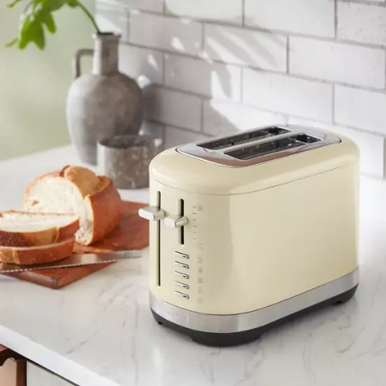 Mandulakrém színű kenyérpirító teljes egészében fém felépítéssel.