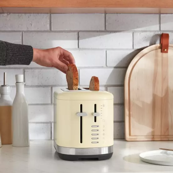 A mandulakrém színű kenyérpirítóba kenyeret helyeznek.