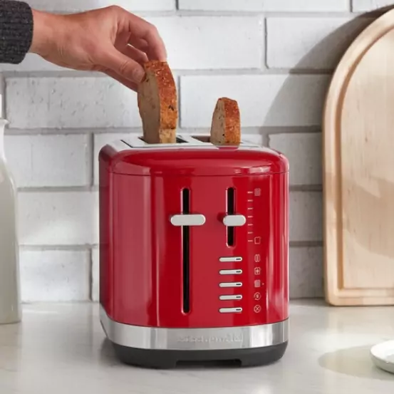 A piros színű kenyérpirítóba kenyeret helyeznek.