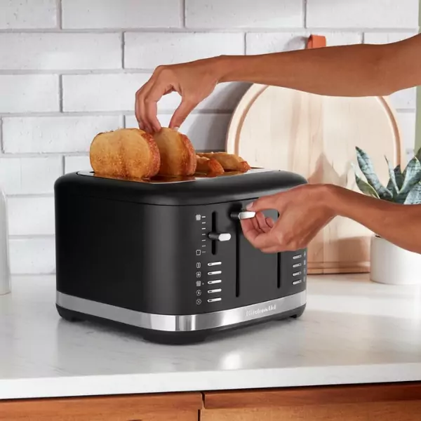 Kiveszik az elkészült kenyeret a fekete, 4-szeletes kenyérpirítóból.